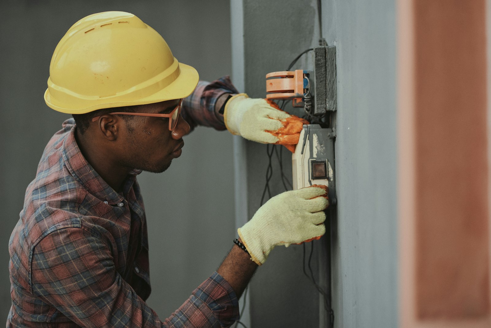 A Copperline electrician in a hard hat and gloves wiring a service box on a Guelph job
