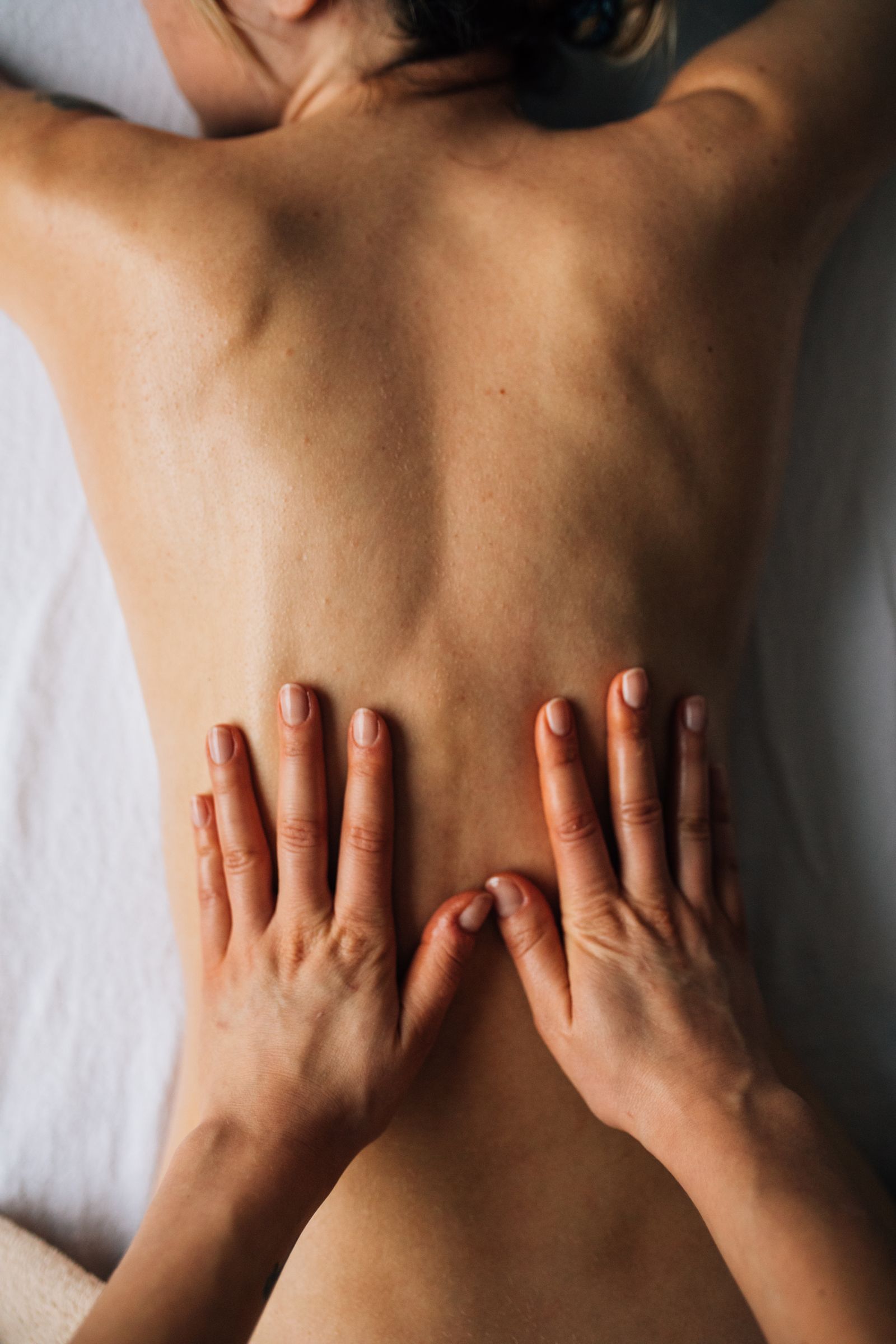 Registered massage therapist applying firm, focused pressure to a client's back on a draped treatment table