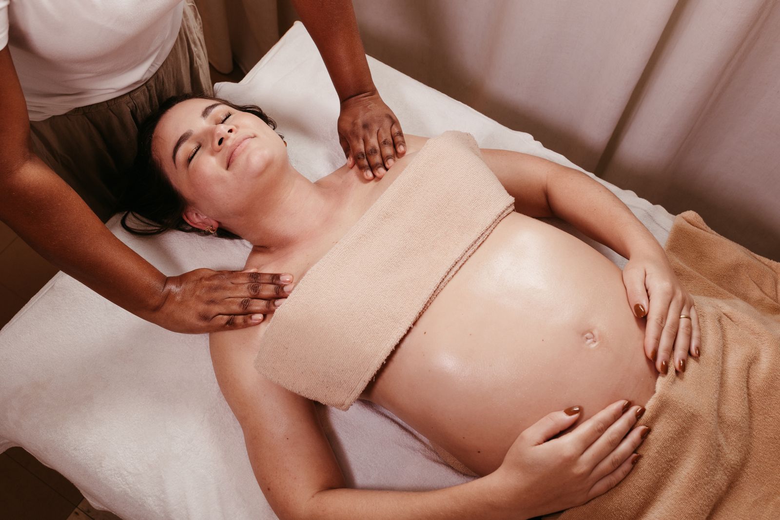 Pregnant client resting comfortably under towel draping during a prenatal massage session