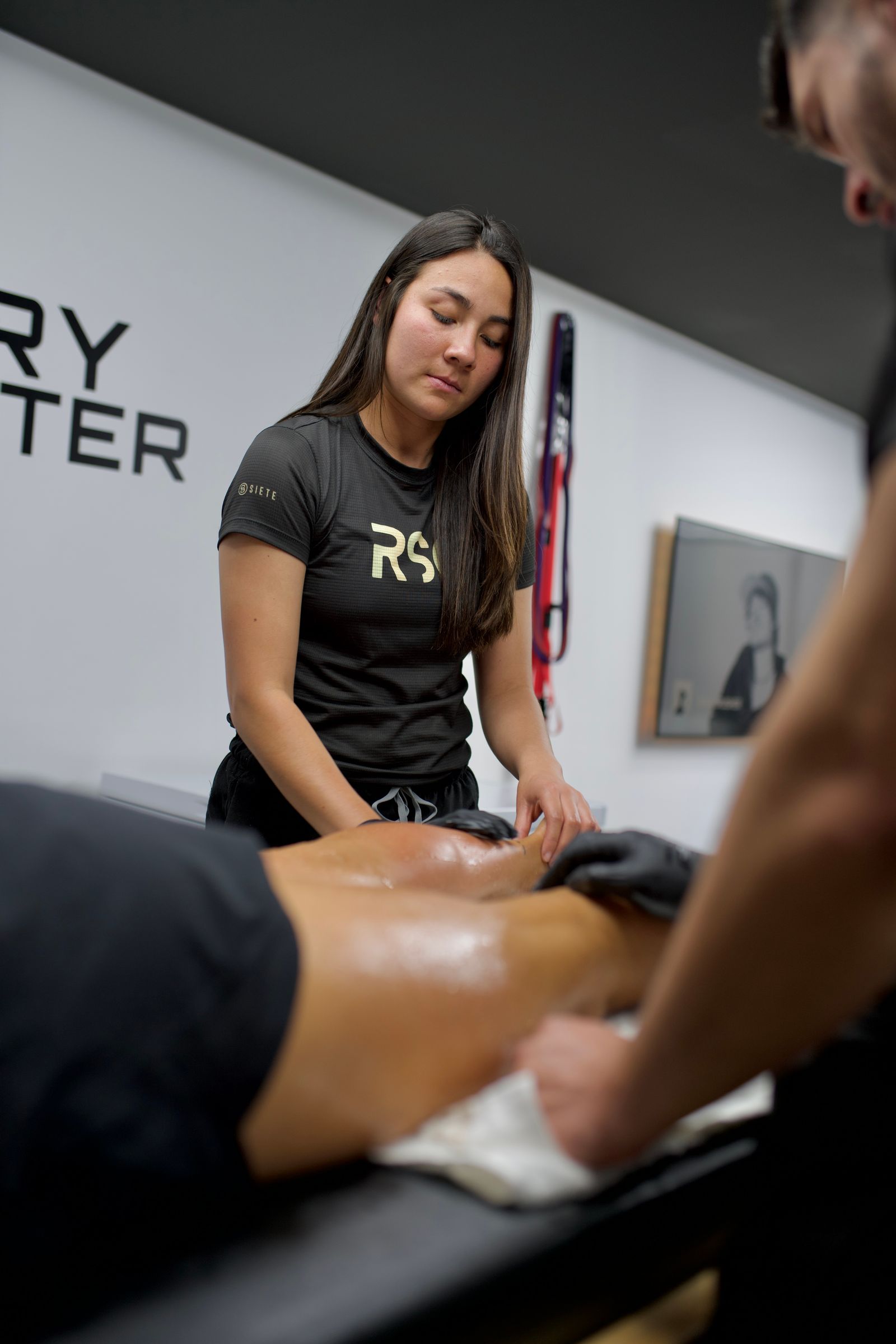 Therapist working on a client's leg during a sports massage session in a clinical treatment space