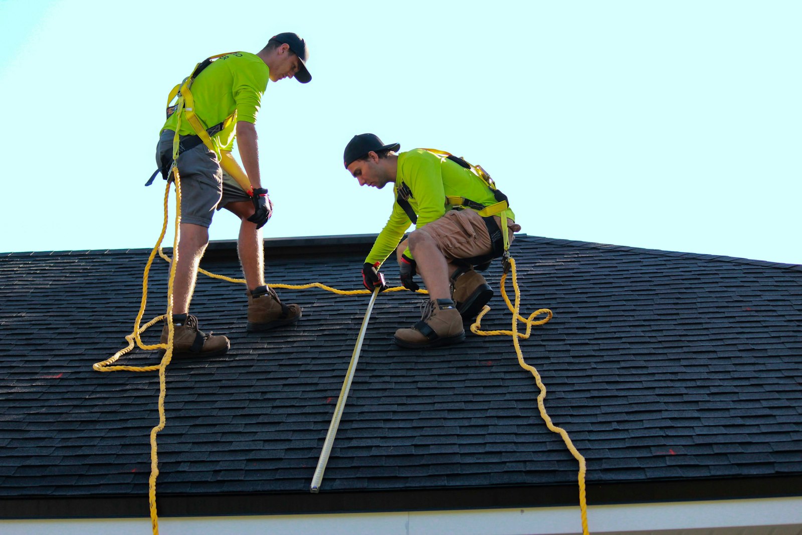 Two Ridgeview crew members measuring a shingle roof on tear-off morning in Peterborough