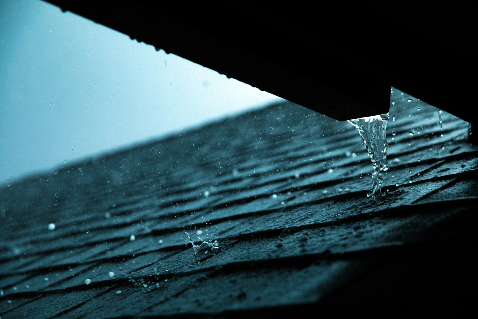 Meltwater running over the shingle eaves of a lakeside roof in Bridgenorth