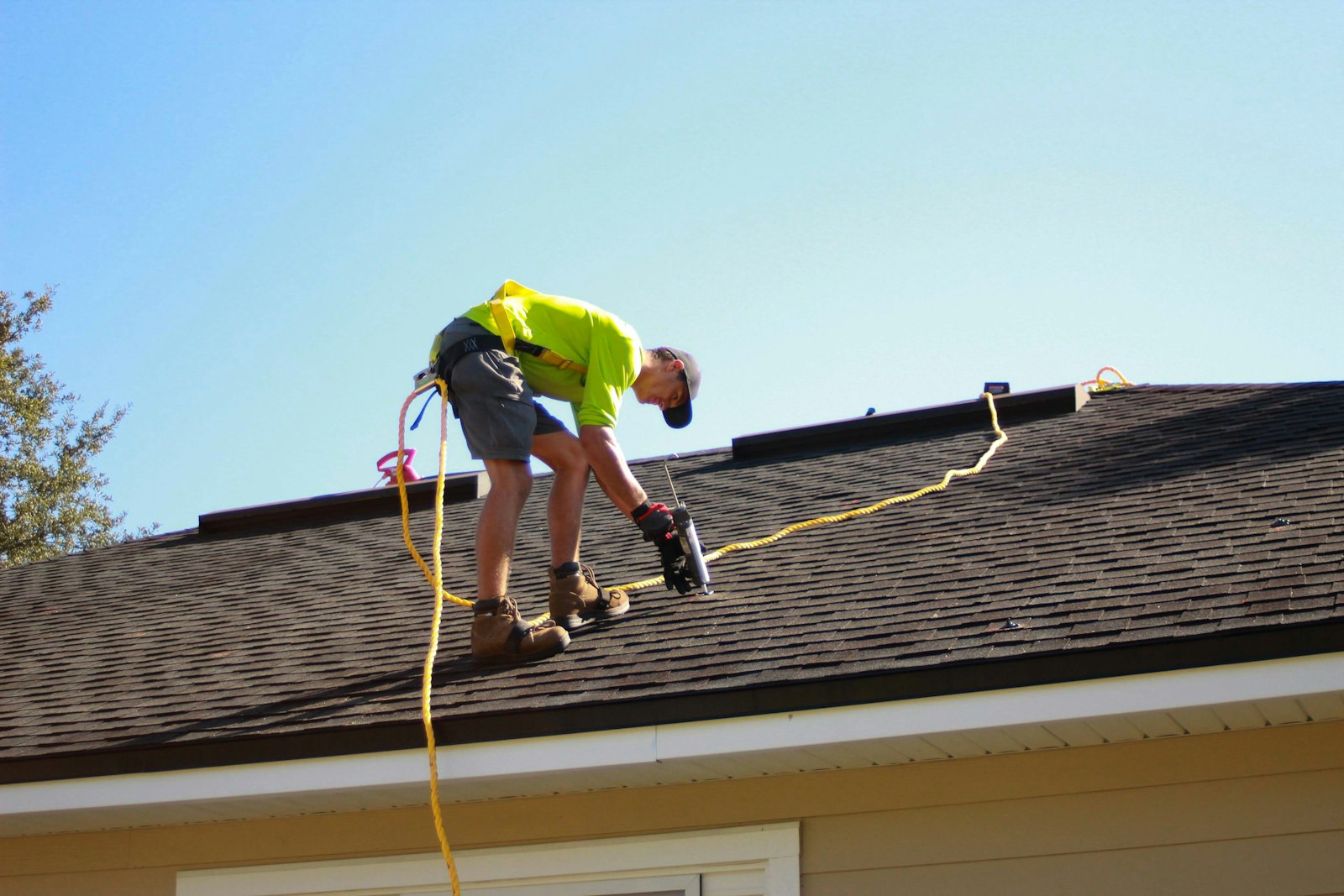 Roofer fastening new architectural shingles at the eaves of a bungalow in Lakefield